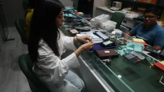 A buyer and a dealer on either side of a glass counter covered in stone trays