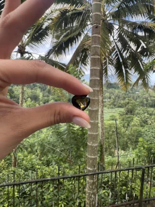 A heart cut stone held up against green hills