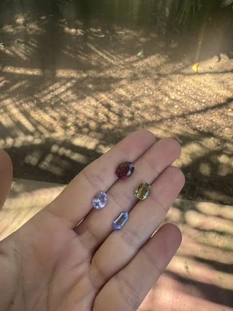 Five cut stones in an open palm in dappled daylight