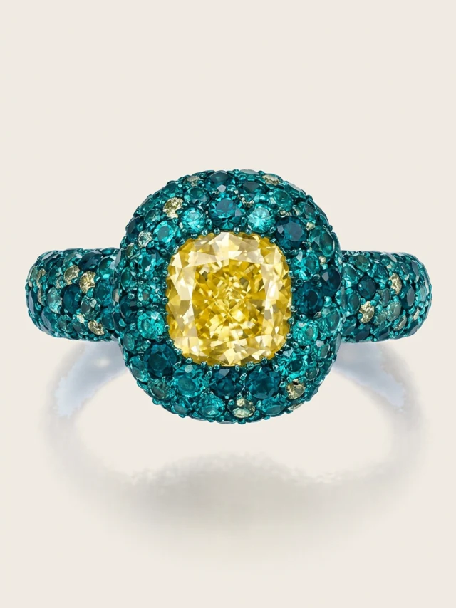Cushion cut diamond ring, yellow toned, inside a teal pavé halo